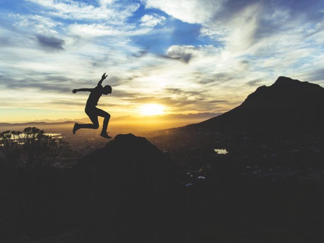 silhouette of man jumping on mountain